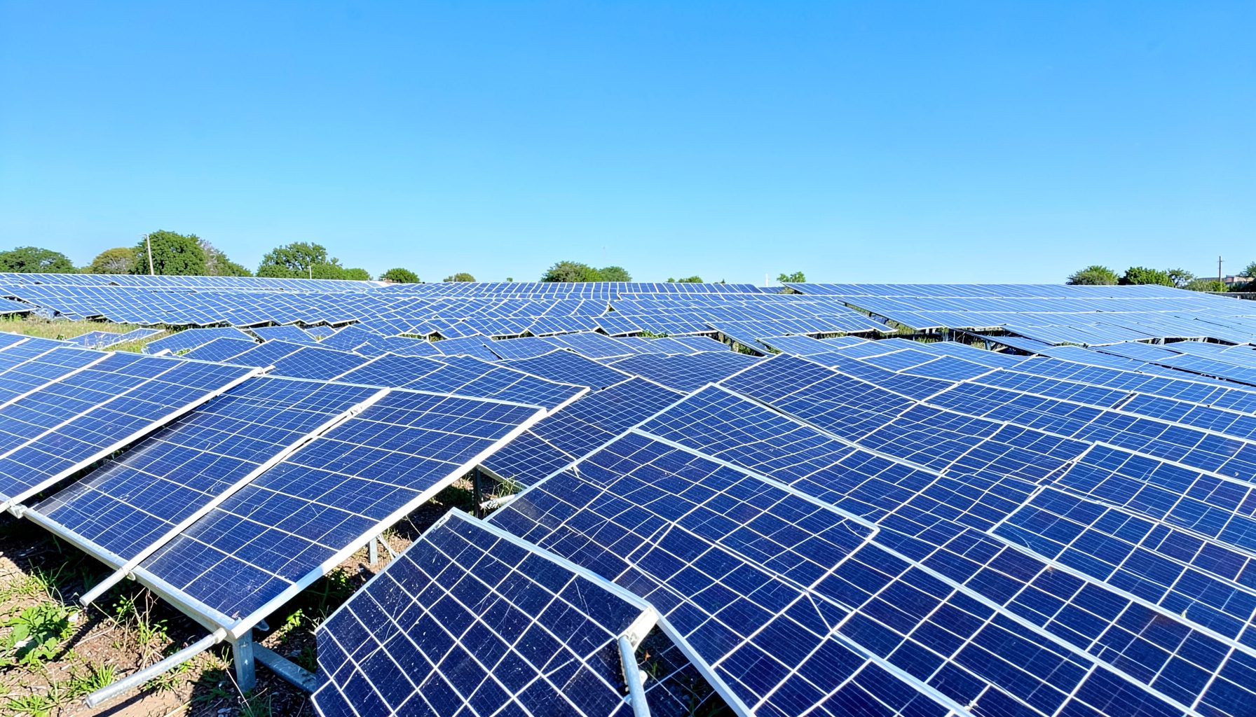 Solar panels arranged in neat rows under a clear blue sky, capturing sunlight in a bright and optimistic scene